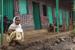 young woman in sudan sitting squatting rain village sleeping